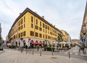 un edificio giallo su una strada di città con persone che camminano di Italianway - Corso Como 12 a Milano