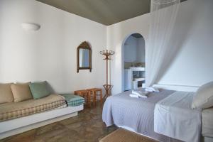 a bedroom with a bed and a couch at Oliaros seaside complex in Agios Georgios