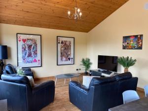 a living room with blue leather furniture and a wooden ceiling at Copper Beech Lodge with Hot Tub in Cupar