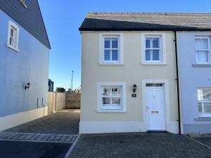 a white house with a white door on a street at Ty Melyn - 2 Bedroom Cottage - Tenby in Tenby