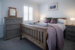 a bedroom with a wooden bed with a dresser and a mirror at Ty Melyn - 2 Bedroom Cottage - Tenby in Tenby