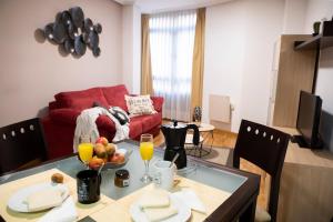 sala de estar con mesa y sofá rojo en Apartamentos Cean Bermudez, en Gijón