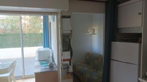 a kitchen with a refrigerator and a couch and a window at Lara 6 - Grand T2 Terrasse Loggia - WC indép - Parking - Quartier calme entre centre-port et île des Loisirs plage Richelieu in Cap d'Agde