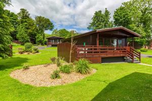 a cabin in a park with a green lawn at Bluebell Lodge 10 with Hot Tub in Newton Stewart