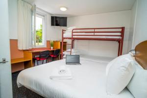 1 dormitorio con 1 cama con ordenador portátil en Quick Palace Pau Zénith, en Pau