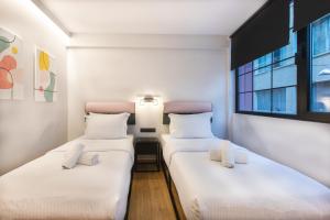 2 camas individuais num quarto com uma janela em PAREA Athens em Atenas