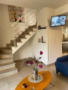 a living room with a staircase and a table with flowers at Casa de tus Sueños Dream Lagoons Veracruz in Veracruz