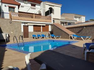 una piscina con sillas azules y un edificio en A 15' Granada, Piscina, Habitaciones Familiares, Futbolín, Casa Medina Güevéjar, en Güevéjar
