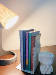 ein Stapel Bücher auf einem Tisch neben einer Lampe in der Unterkunft My Own Hotel-like Studio Apartment. Near Unpad! in Cilimus 2