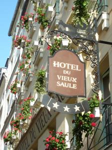 a sign on the side of a building with flowers at Hôtel Du Vieux Saule in Paris