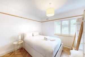- une chambre blanche avec un lit et une fenêtre dans l'établissement Stunning 2 bed flat in Richmond, à Kew