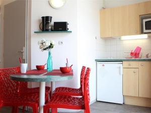 eine Küche mit einem Tisch mit roten Stühlen und eine Küche mit einem Kühlschrank in der Unterkunft Appartement La Rochelle, 1 pièce, 4 personnes - FR-1-246-9 in La Rochelle