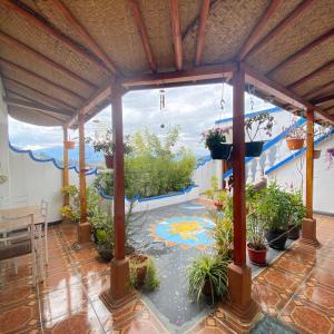 une grande terrasse avec des plantes en pot et une grande fenêtre. dans l'établissement Hostal Chasqui, à Otavalo