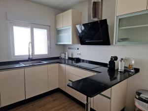 a kitchen with white cabinets and a black counter top at Sunset Apartment in Huelva