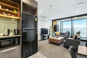 uma cozinha e sala de estar com um sofá e uma mesa em Valley View Apartment with Mountain Views & Wi-Fi em Auckland