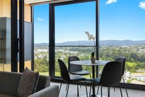 uma mesa e cadeiras num quarto com janelas grandes em Valley View Apartment with Mountain Views & Wi-Fi em Auckland
