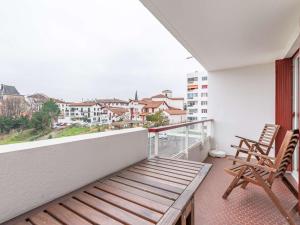 un balcón con un banco de madera y sillas. en Studio Hendaye, 1 pièce, 3 personnes - FR-1-2-304, en Hendaya