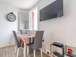 a dining room with a table and chairs and a clock at Studio Hendaye, 1 pièce, 3 personnes - FR-1-2-304 in Hendaye