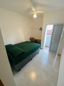 a bedroom with a green bed and a sliding glass door at Ap no centro piscina e churras in Ubatuba