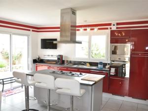 une cuisine avec des placards rouges et des tabourets blancs dans l'établissement Maison Pleumeur-Bodou, 4 pièces, 6 personnes - FR-1-368-13, à Pleumeur-Bodou