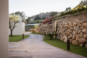 une passerelle à côté d'un mur en pierre dans l'établissement Armacera Resort, à Zambrone