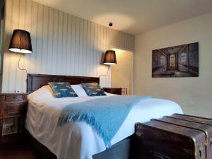 a bedroom with a bed with a blue blanket and two lamps at Maison Egalité in Melay