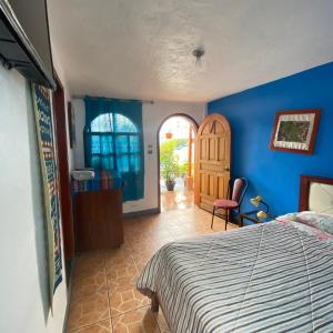 1 dormitorio con cama y pared azul en Hostal Chasqui, en Otavalo