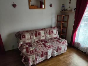 ein Wohnzimmer mit einer Couch mit einer Decke drauf in der Unterkunft Studio Les Contamines Montjoie - Les Combettes - Le Lay - WIFI INCLUS in Les Contamines-Montjoie