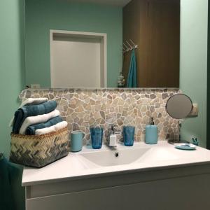 een wastafel in de badkamer met een mand met handdoeken en een spiegel bij Casa Sandra Elisa in Maasmechelen