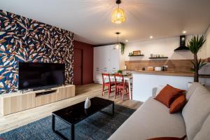 een woonkamer met een bank en een tv en een keuken bij Jolie Maison de ville proche centre-ville in Avignon