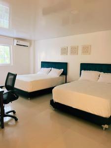 2 Betten in einem Zimmer mit einem Schreibtisch und einem Stuhl in der Unterkunft Apartahotel Plaza in San Andrés