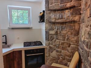 une cuisine avec un mur en pierre et des verres sur le mur dans l'établissement House for rent Didova kuća, à Makarska