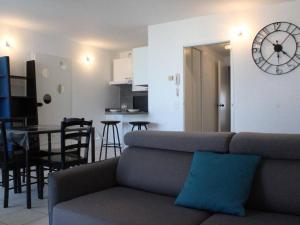 ein Wohnzimmer und eine Küche mit einem Sofa und einer Uhr in der Unterkunft Appartement La Rochelle, 2 pièces, 4 personnes - FR-1-246-310 in La Rochelle