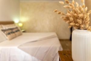 Un jarrón blanco con flores en una habitación con cama en Little Flower, en Alghero