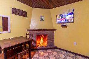 um quarto com uma lareira com uma mesa e uma televisão em Pousada Chalana em Monte Verde