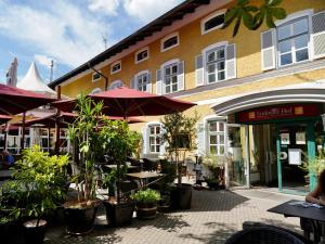 un restaurant avec des tables et des parasols en face d'un bâtiment dans l'établissement Hotel Endorfer Hof, à Bad Endorf