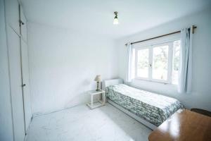 Habitación blanca con cama y ventana en Casa duplex 2 dormitorios by depptö, en Punta del Este