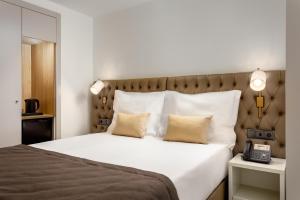 a bedroom with a large white bed with a telephone at Empire Marquês Hotel in Lisbon