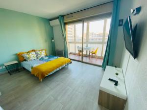 a bedroom with a bed and a large window with a table at Coquet logement front de mer in Cagnes-sur-Mer