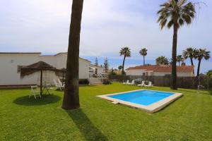 einen Garten mit Pool und Palmen in der Unterkunft VILLA LUNA Beach Premium 9PAX in Torre de Benagalbón