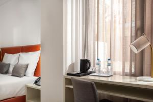 a hotel room with a bed and a desk with water bottles at Empire Marquês Hotel in Lisbon