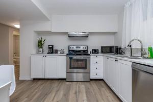een keuken met witte kasten en een fornuis met oven bij *Modern & Cozy* Basement 1 Bdrm W/Fast Internet & Smart TV in Barrie