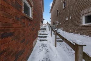 a snow covered sidewalk next to a brick building at *Modern & Cozy* Basement 1 Bdrm W/Fast Internet & Smart TV in Barrie