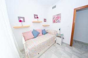 um quarto com uma cama com almofadas cor-de-rosa e azuis em MI RETIRO SEVILLANO em Sevilha