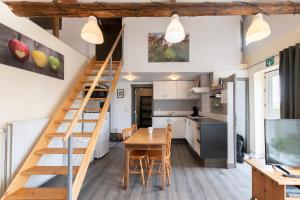 a kitchen and dining room with a staircase in a tiny house at DE SMISHOEVE met speelruimte, dieren en wellness in Heers