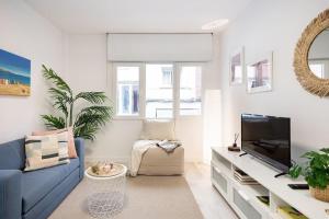 a living room with a blue couch and a tv at Piso en el corazón de Gijón in Gijón