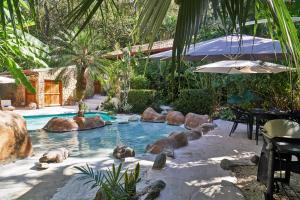 einen Pool mit Steinen und einem Regenschirm in einem Hof in der Unterkunft Havana Lodge in Mal País