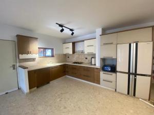 a large kitchen with wooden cabinets and a refrigerator at Vila kasa vali in Zekharya