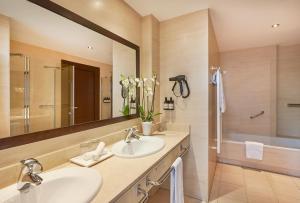 a bathroom with two sinks and a large mirror at NH Collection León Plaza Mayor in León