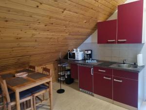 cocina con armarios rojos y techo de madera en Apartma Take It Easy en Bled